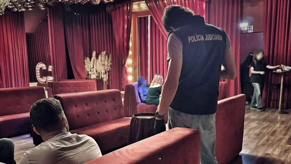 Agent de la police judiciaire portugaise dans un établissement au décor rouge.