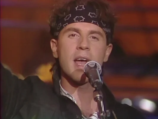 Le chanteur de Raft en plein concert, capturé dans une ambiance lumineuse tamisée.