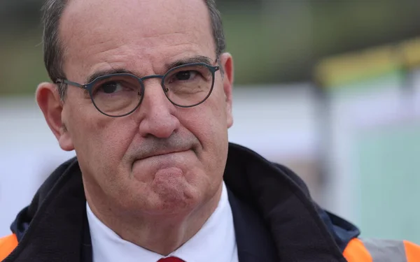Jean Castex en gilet de sécurité orange, regard sérieux.