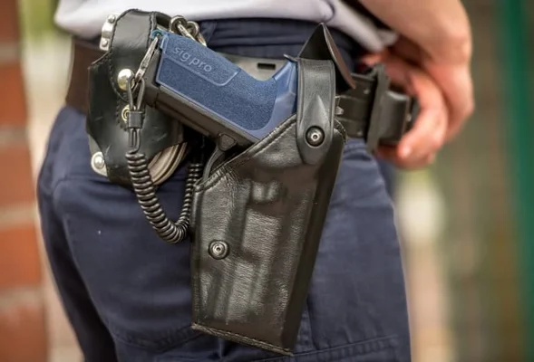 Détail d'un pistolet Sig Pro dans son étui sur le ceinturon d'un agent.