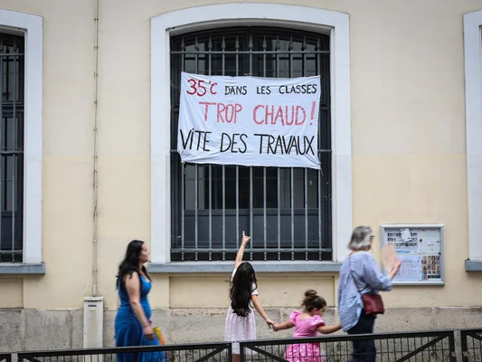 Banderole de protestation contre la chaleur dans une salle de classe, accrochée à une fenêtre.