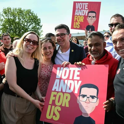 Andy Burnham avec des partisans tenant des pancartes de campagne.