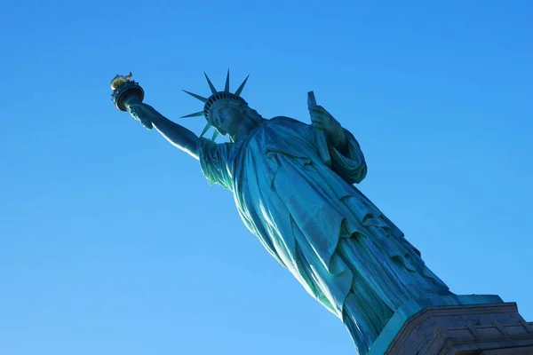 La statue de la Liberté, monument emblématique de New York, vue depuis un angle bas sous un ciel dégagé.