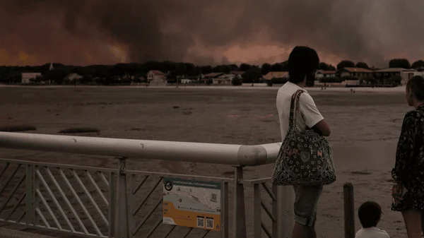 Des habitants et touristes du Cap-Ferret, impuissants, contemplent l'incendie qui les force à fuir par la mer.