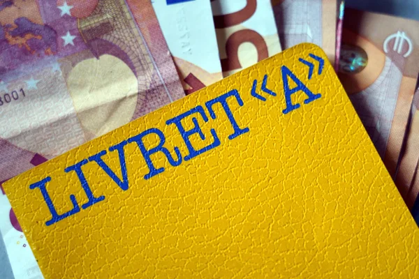 Livret A jaune sur des billets, symbole de l'épargne des Français.
