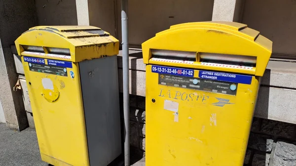 Deux boîtes aux lettres jaunes à Lourdes, dont l'une semble déjà condamnée.