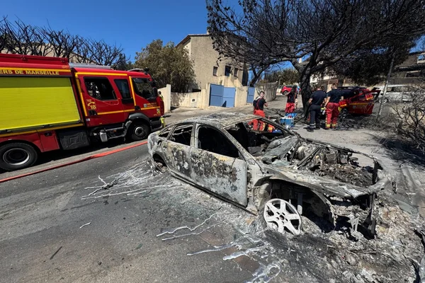 Une voiture calcinée et des pompiers de Marseille sur les lieux d'un incendie.