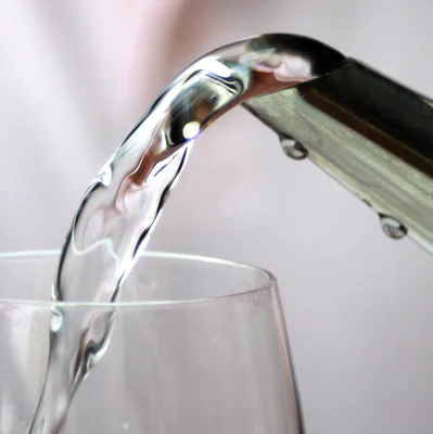 Eau claire s'écoulant d'un robinet métallique dans un verre transparent.