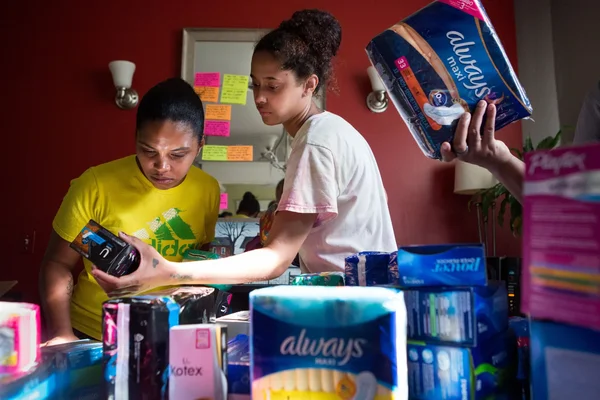 Personnes organisant différentes marques de protections menstruelles sur une table.