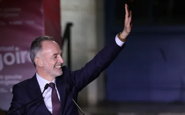Un responsable municipal souriant au podium lors de la séance du Conseil de Paris où la citoyenneté d'honneur a été attribuée.