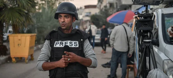 Reporter en zone de conflit, portant un gilet 'PRESS', symbole des journalistes palestiniens honorés.