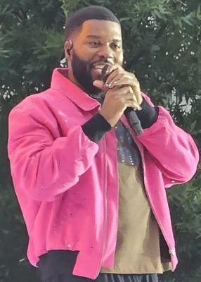 Khalid en concert, veste rose et micro en main.