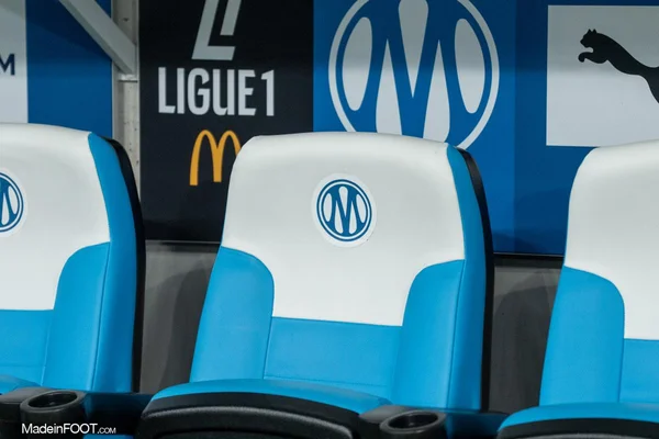 Banc de touche de l'OM avec le logo du club et le branding Ligue 1.