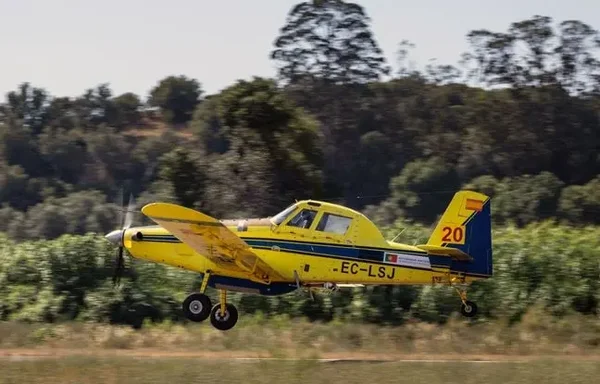 Un avion bombardier d'eau survole une zone agricole pour lutter contre les incendies.