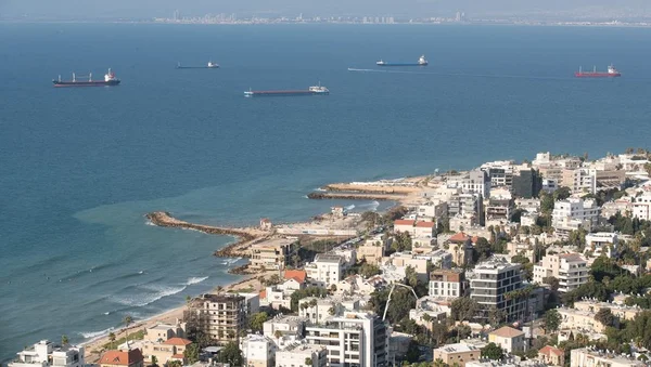 Ville côtière israélienne avec cargos ancrés au large, vue aérienne.