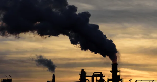 Installation industrielle avec cheminées rejetant de la fumée, symbole des émissions de CO2.