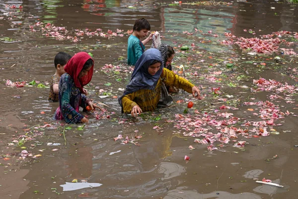 Des enfants et des femmes dans une rue inondée, récupérant des aliments dans les eaux de crue.