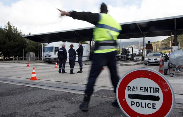 Contrôle aux frontières : des policiers dirigent la circulation à un péage.