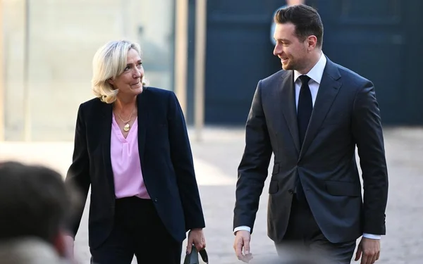 Marine Le Pen et Jordan Bardella marchant en extérieur.