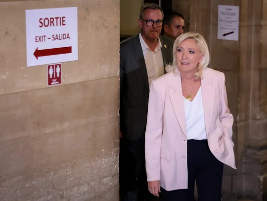Marine Le Pen quittant le tribunal, entourée de deux hommes en costume.