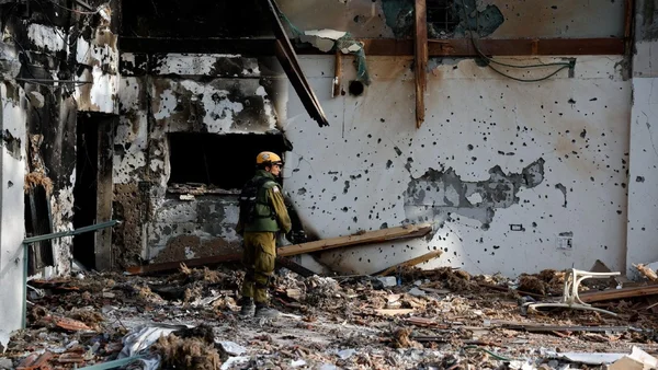 L'intérieur dévasté d'un bâtiment après l'attaque du 7 octobre, avec un secouriste en tenue de protection.