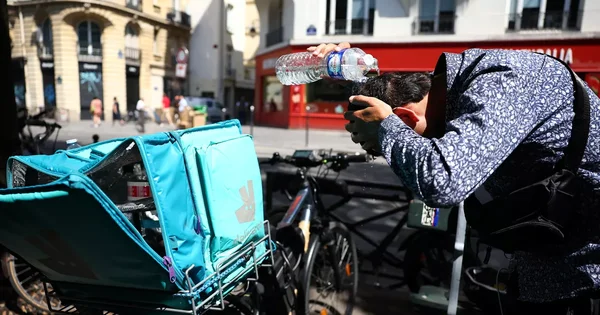 Livreur à vélo se rafraîchissant pendant la canicule en ville.