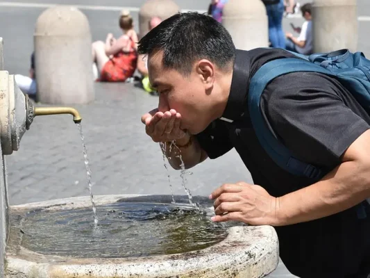 Un homme boit de l'eau à une fontaine publique, image de la recherche d'eau lors de la sécheresse.