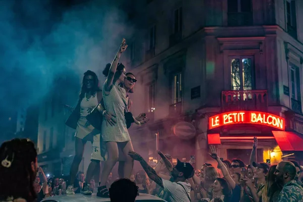Des fêtards dansent sur le toit d'une voiture lors de la fête de la musique, illustrant les débordements évoqués.