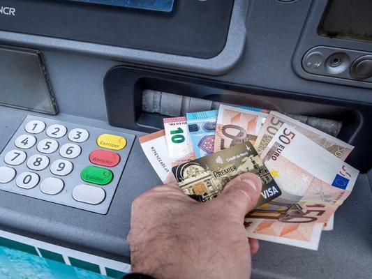 Carte Visa Premier et billets en euros à la sortie d'un distributeur.