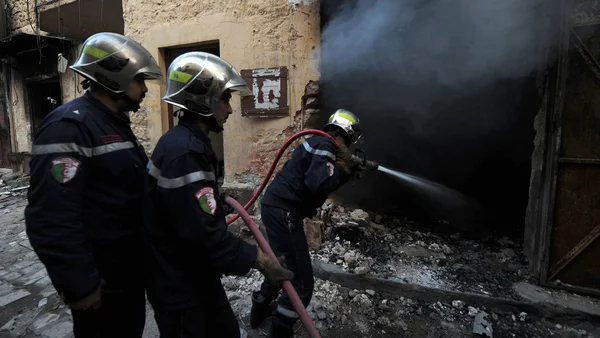 Pompiers intervenant pour éteindre un incendie dans un bâtiment endommagé.