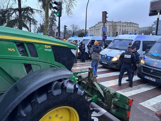 Tracteur agricole bloquant une rue parisienne face aux CRS, lors d'une manifestation d'agriculteurs.