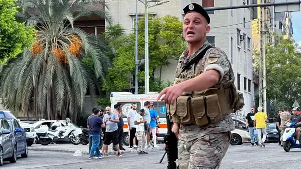 Soldat libanais sur une rue après un incident, entouré de civils et de secours.