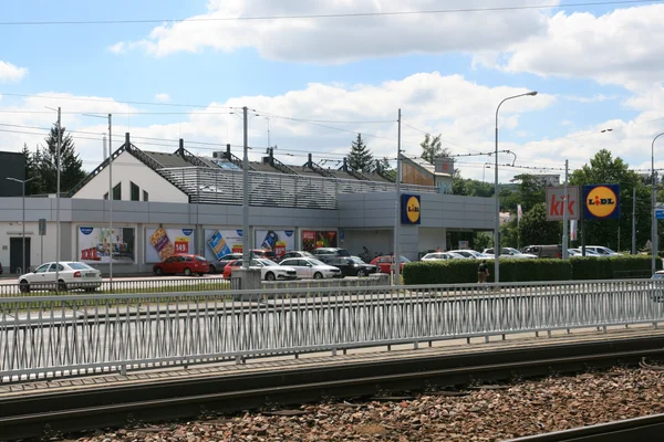 Vue extérieure d'un supermarché Lidl à Brno-Bystrc, en République tchèque, avec des voitures garées et des voies de tramway.