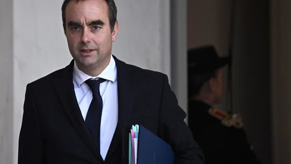 Sébastien Lecornu, ministre de l'Agriculture, portant un dossier devant un garde républicain.