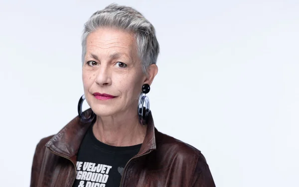Lio, les cheveux gris courts, en veste de cuir, dans un portrait studio.