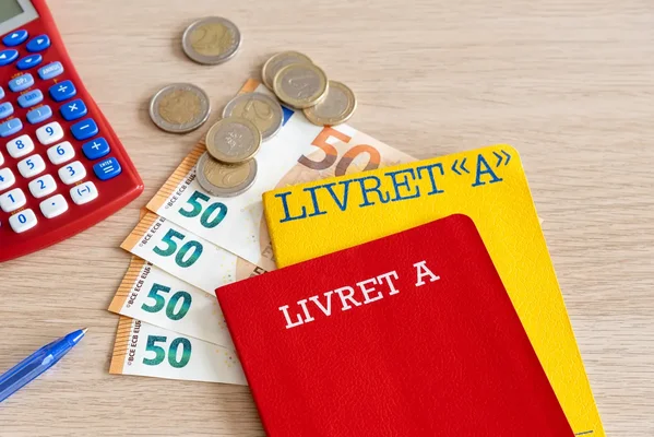 Livrets A, billets et pièces illustrant l'épargne et les retraits.