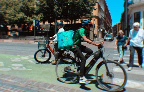Livreurs à vélo sur une piste cyclable en ville.