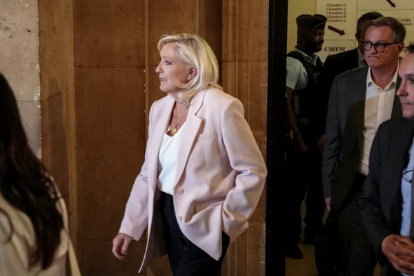 Marine Le Pen sort du tribunal, entourée de son équipe et d'un agent de sécurité.
