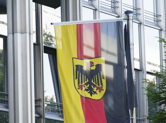 Drapeau allemand avec l'aigle fédéral flottant devant un bâtiment institutionnel à Berlin.