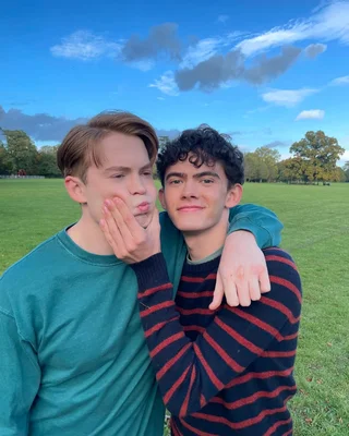 Nick et Charlie partagent un moment complice dans un parc, souriant à la caméra.