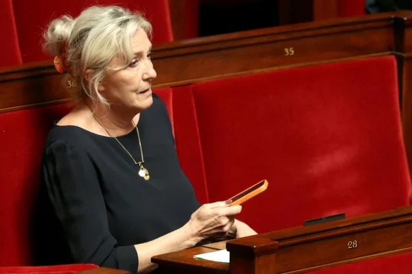 Marine Le Pen dans l'hémicycle, consultant son téléphone avant l'audience.