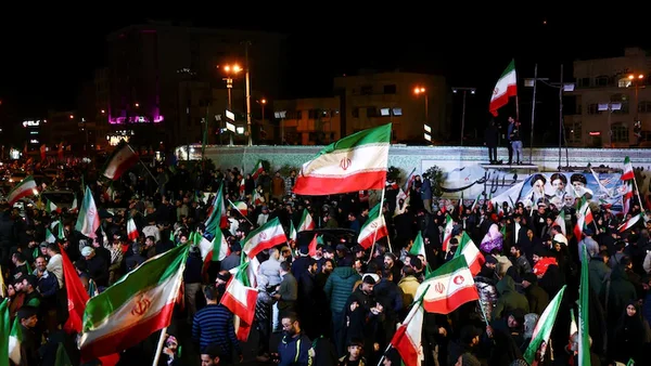 Rassemblement nocturne de soutien au cessez-le-feu entre les États-Unis et l’Iran, avec des drapeaux iraniens agités par la foule.