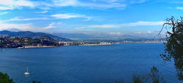 Vue panoramique de la mer au large de Cannes, avec un voilier solitaire.