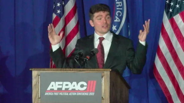 Nick Fuentes à la conférence AFPAC 2022, entouré de drapeaux américains.