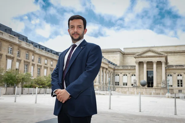 Jordan Bardella devant un bâtiment classique.