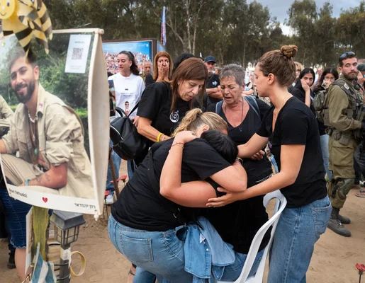 Des proches en deuil un an après l'attaque du 7 octobre, se réconfortant devant le portrait d'une victime.