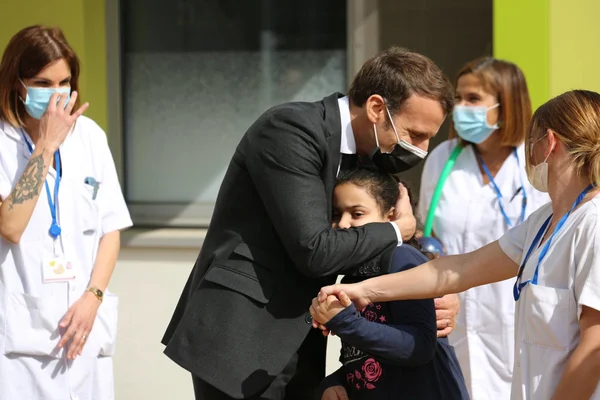 Emmanuel Macron en Isère en avril 2021, lors d'une visite consacrée à l'autisme, étreignant une jeune fille devant un centre spécialisé.