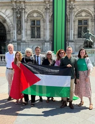 Manifestants tenant le drapeau palestinien devant un bâtiment historique, en soutien à la décision de la Ville de Paris.