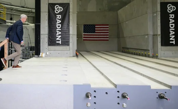 Visiteur montant sur une plateforme dans une installation de réacteurs nucléaires, avec des bannières 'RADIANT'.