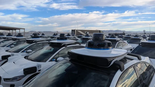 Flotte de robotaxis Waymo basés sur la Jaguar I-PACE stationnés dans un parc extérieur.